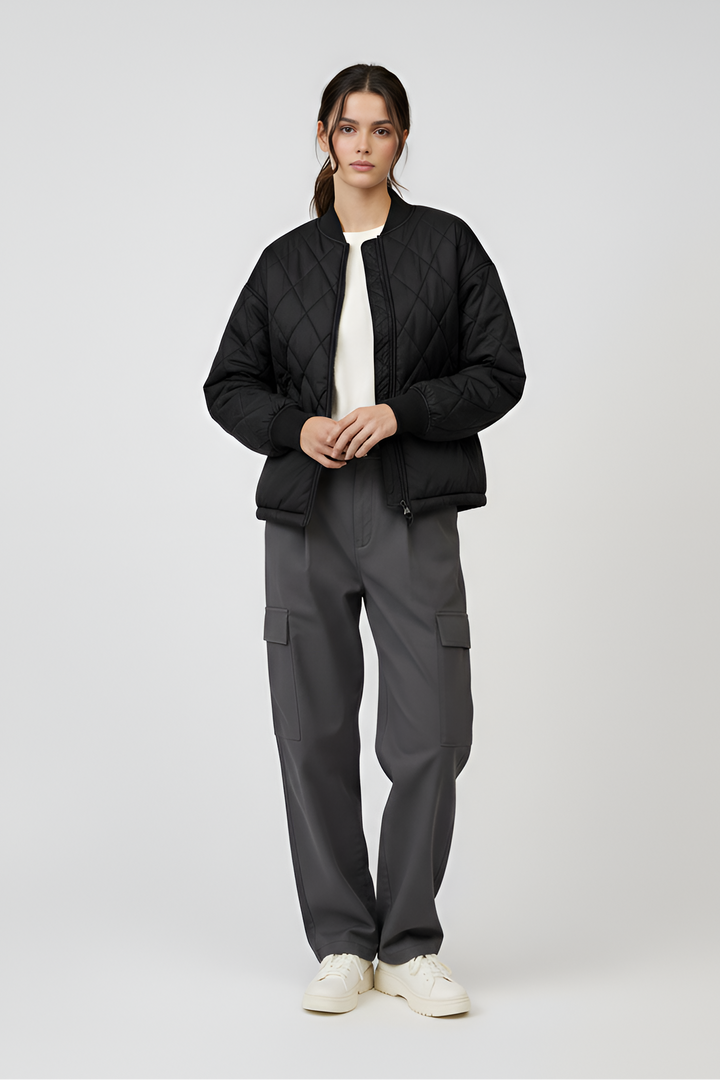 Person wearing a black puffer jacket and gray cargo pants on a white background