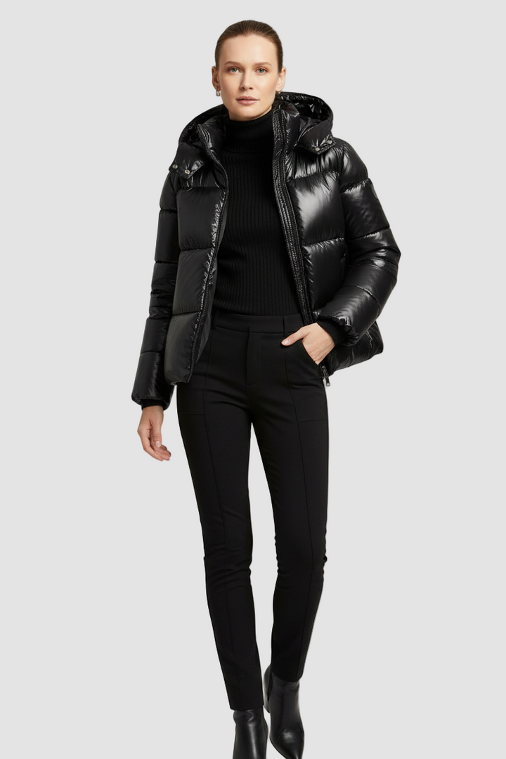 Person wearing a black puffer jacket, black top, and black pants on a white background