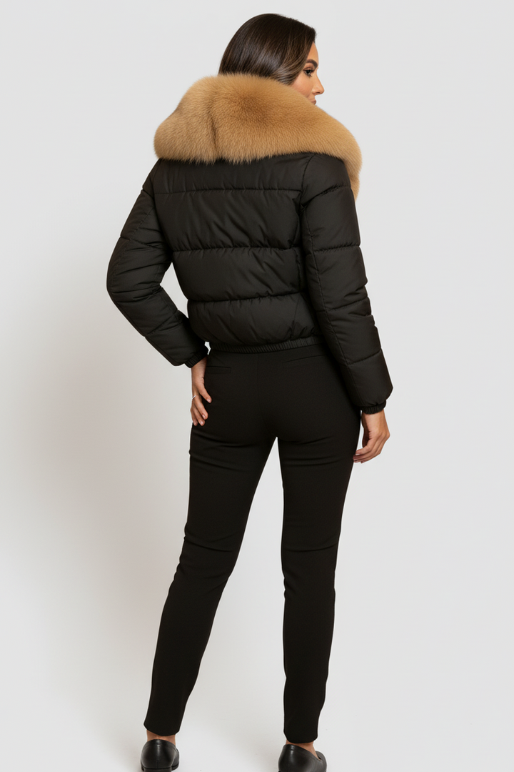 Person wearing a black puffer jacket with a fur-lined hood on a white background