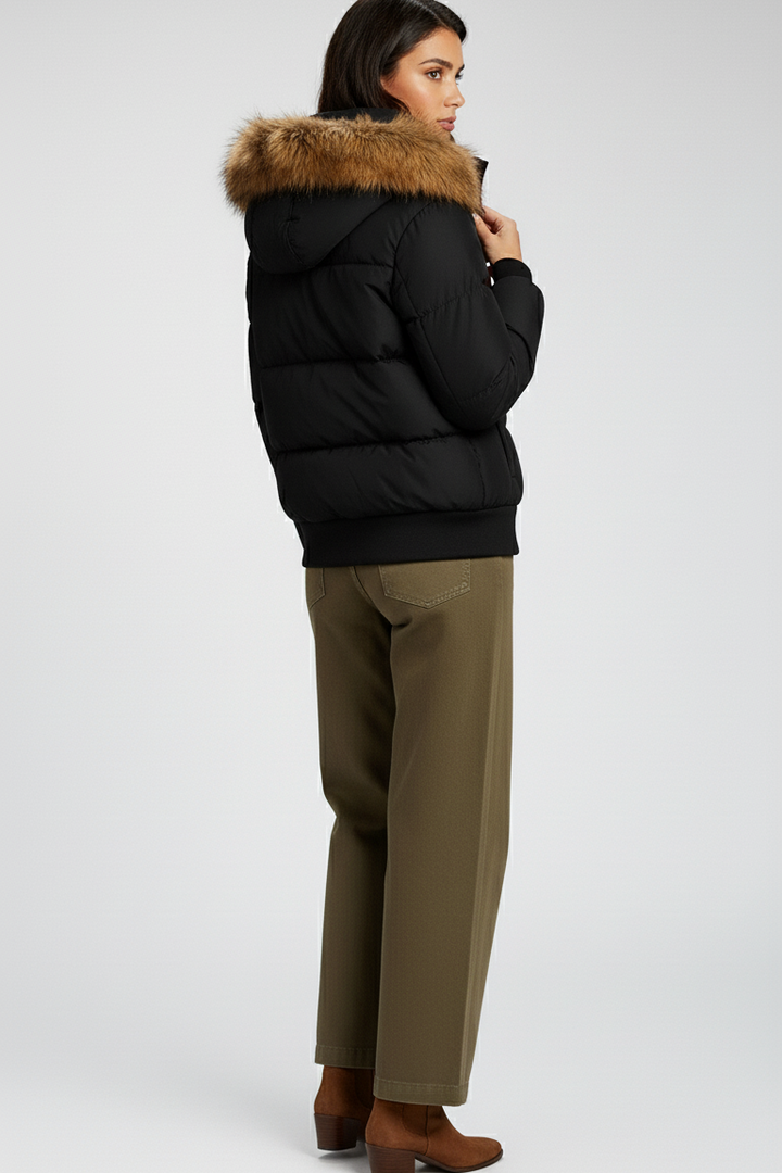 Person wearing a black puffer jacket with fur hood on a white background