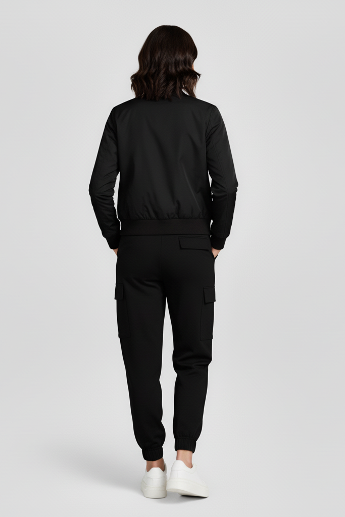 Person wearing a black tracksuit on a light gray background