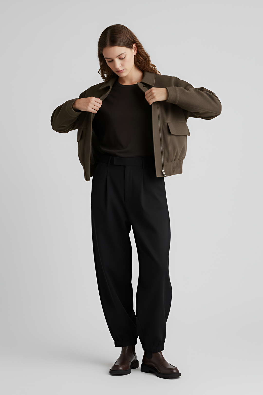 Person wearing a brown jacket over a black outfit on a light gray background