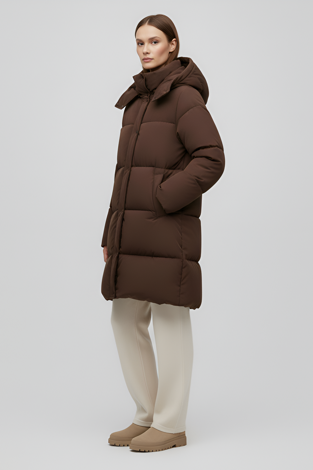 Person wearing a brown puffer coat on a white background