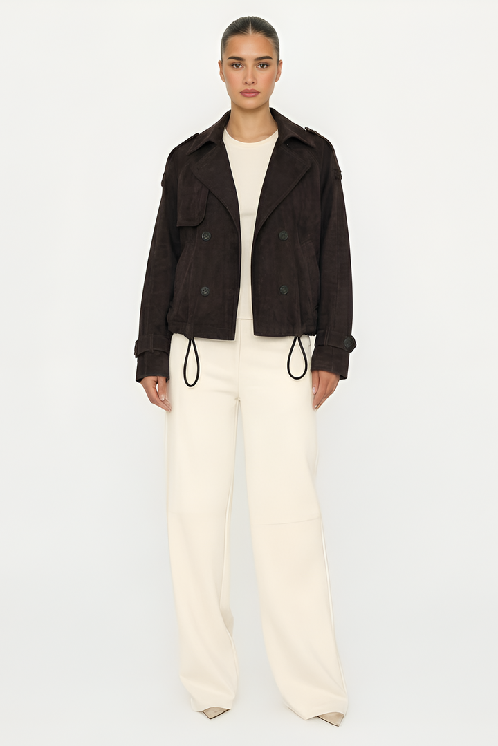 Person wearing a dark jacket and white pants on a light gray background