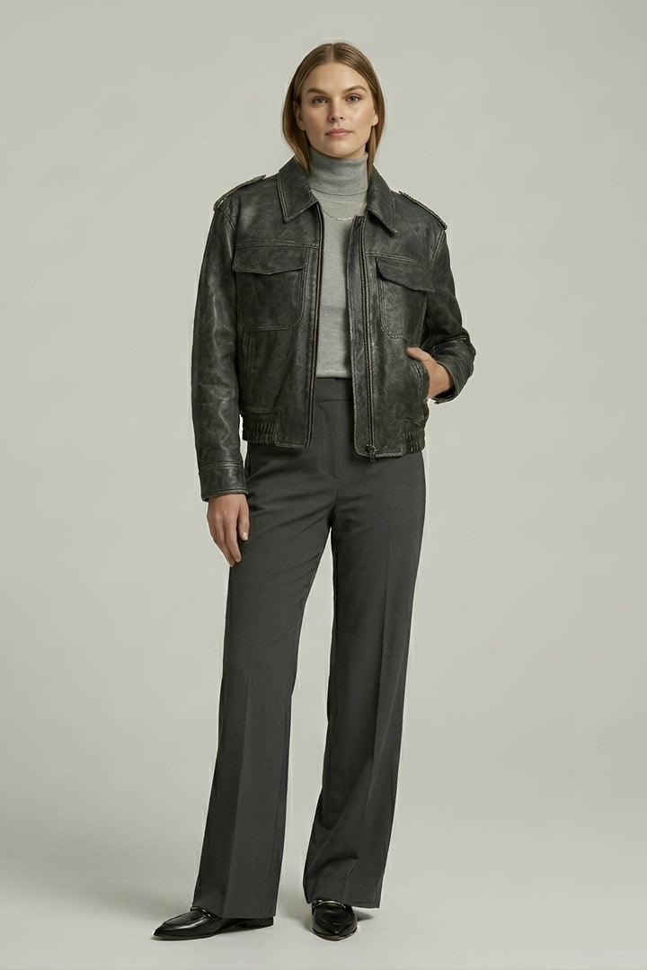 Person wearing a dark leather jacket and gray pants on a plain background