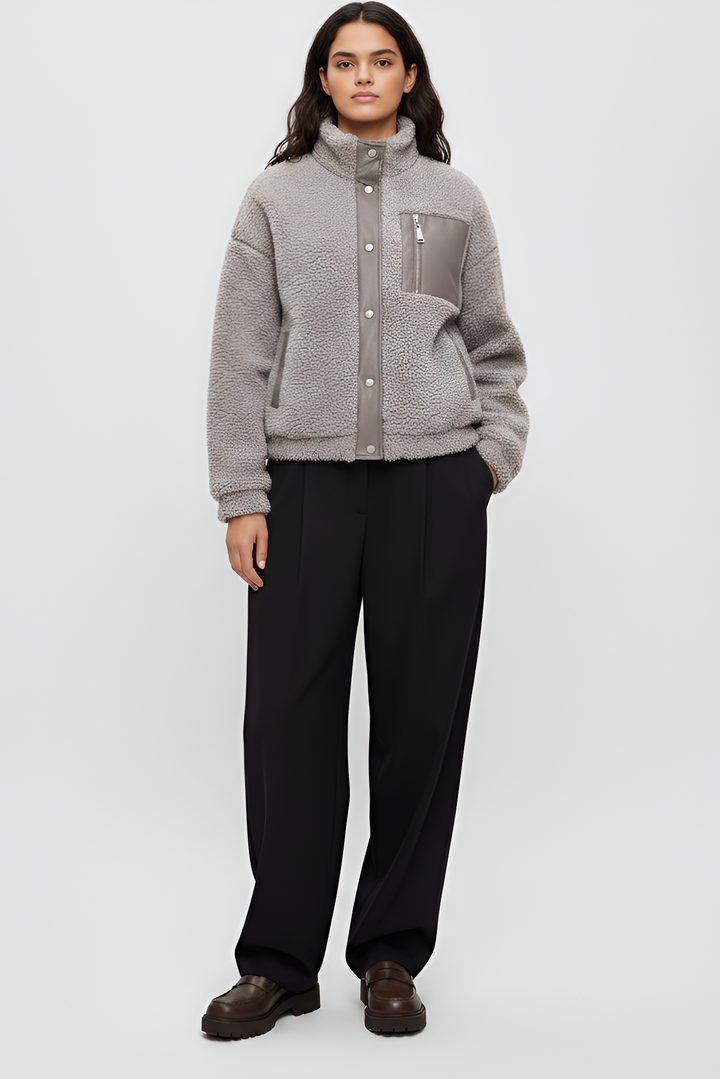 Person wearing a gray fleece jacket and black pants on a white background