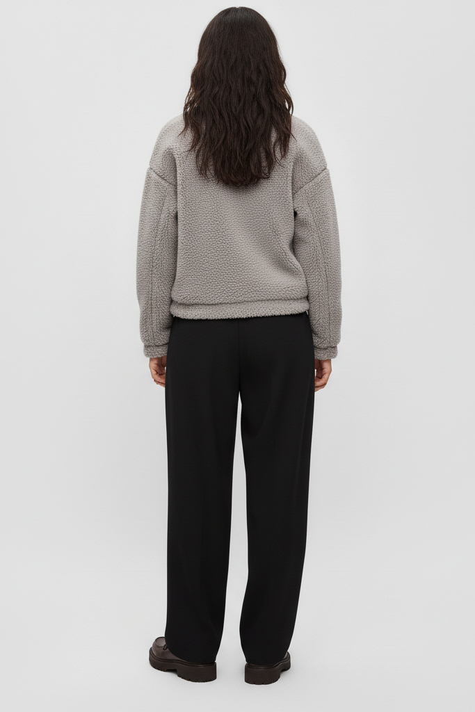 Person wearing a gray sweater and black pants on a white background