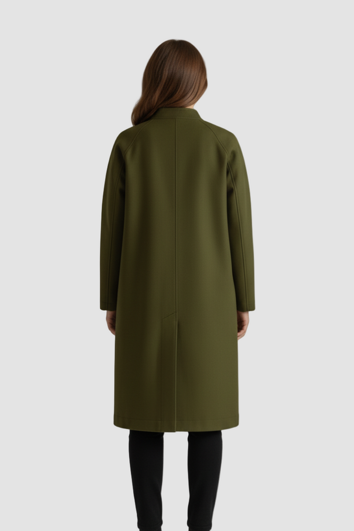 Person wearing a green coat standing against a plain background