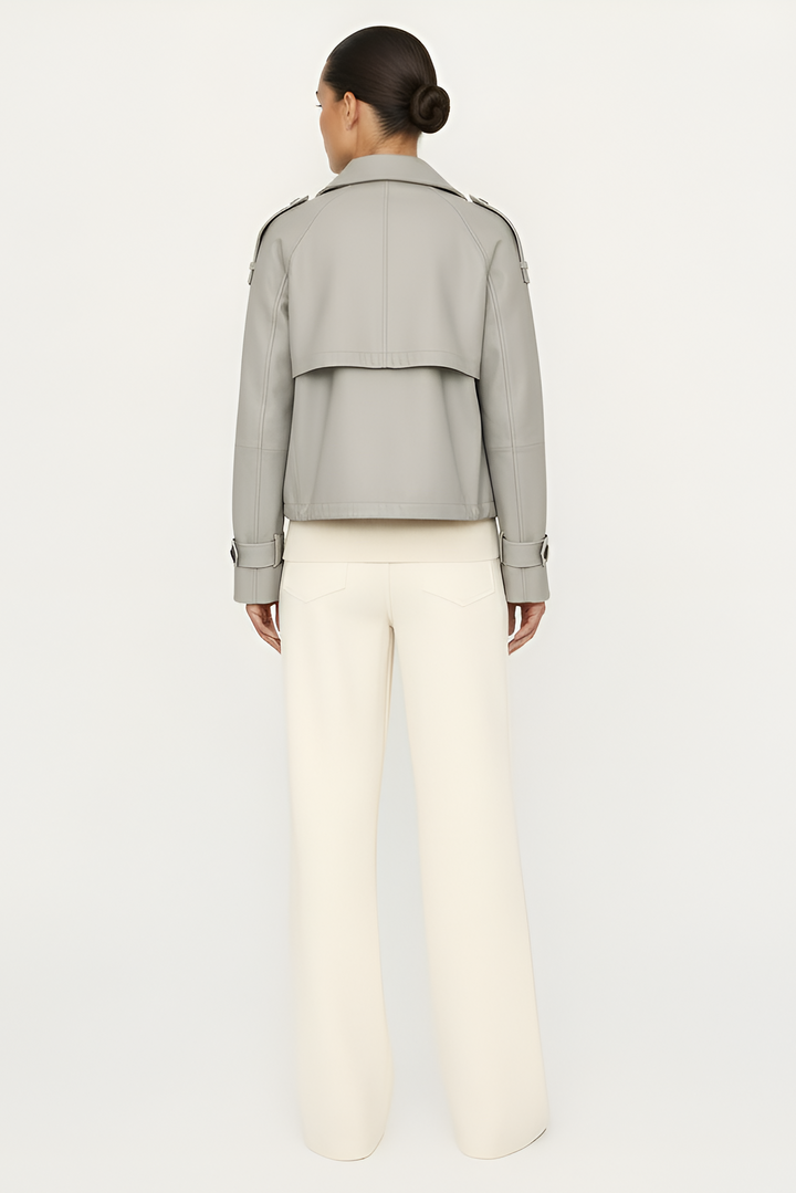 Person wearing a light gray jacket and white pants on a plain background