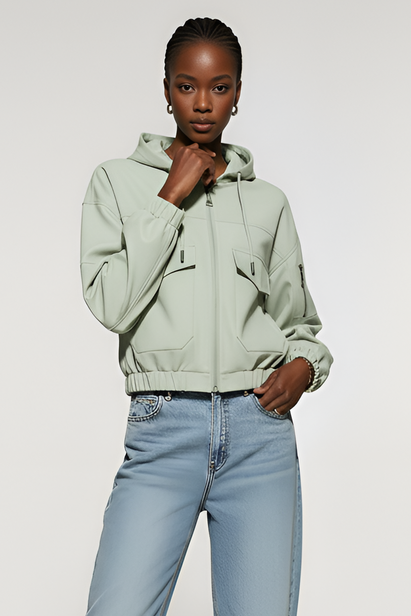 Person wearing a light green hoodie and blue jeans on a white background