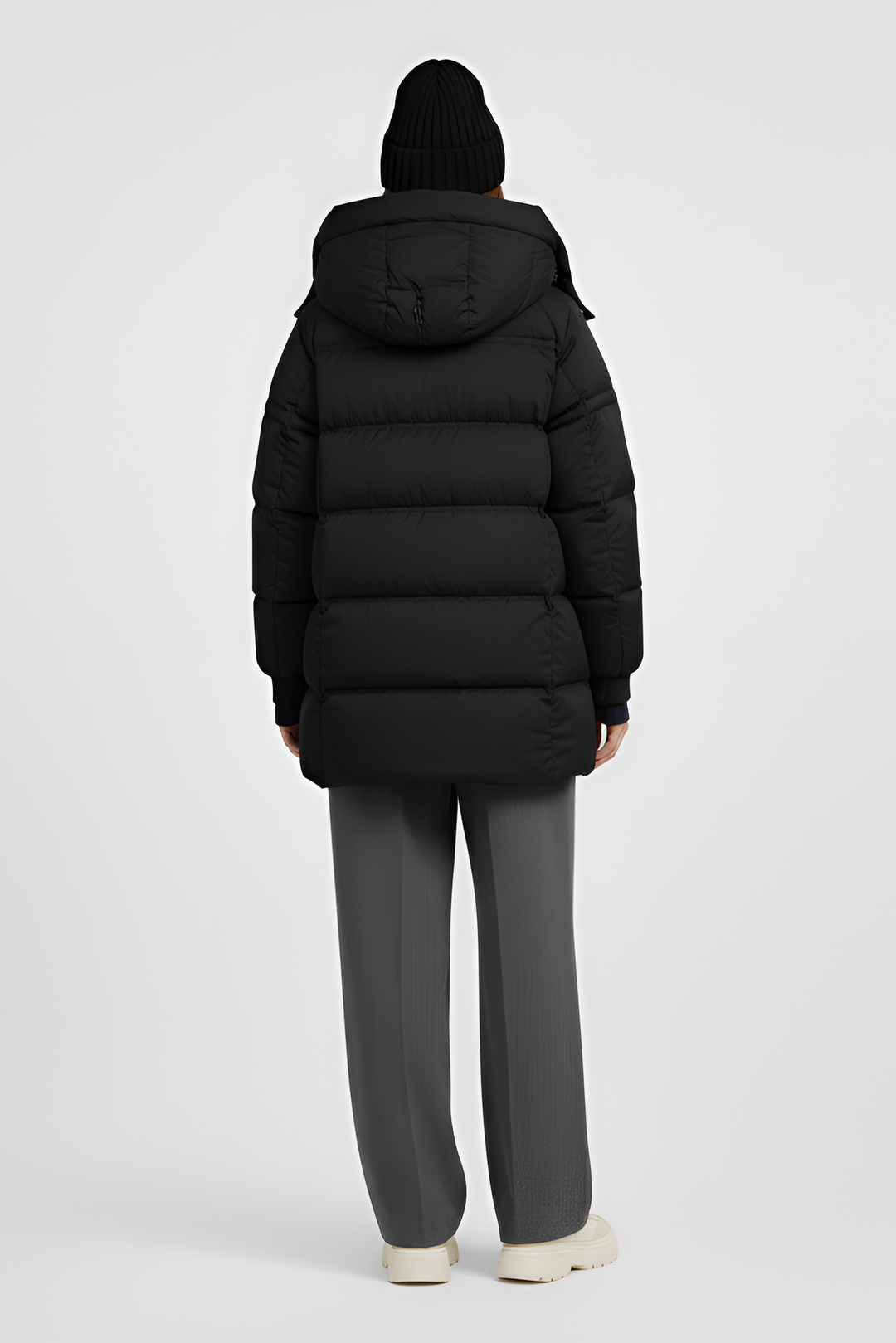 Person wearing a long black puffer coat on a light gray background