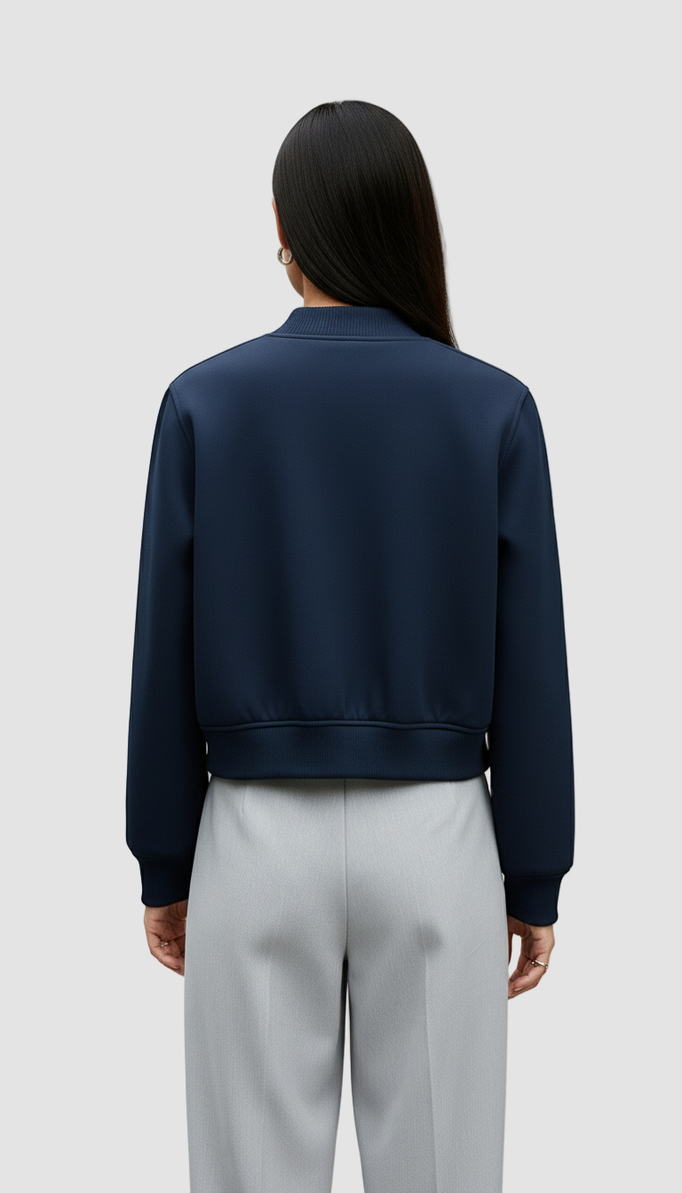 Person wearing a navy blue jacket and light gray pants on a plain background