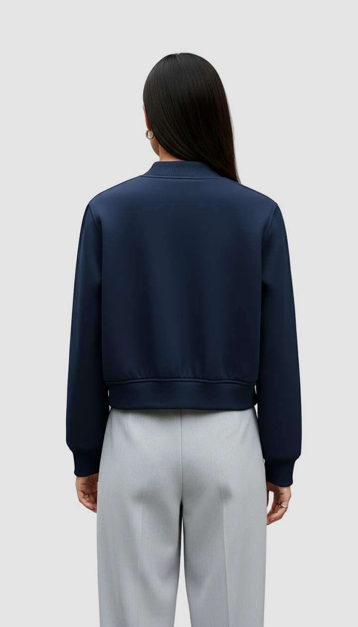 Person wearing a navy blue jacket and light gray pants on a plain background