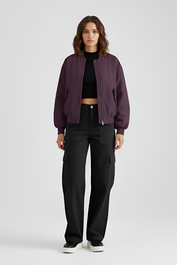 Person wearing a purple jacket and black pants on a light gray background