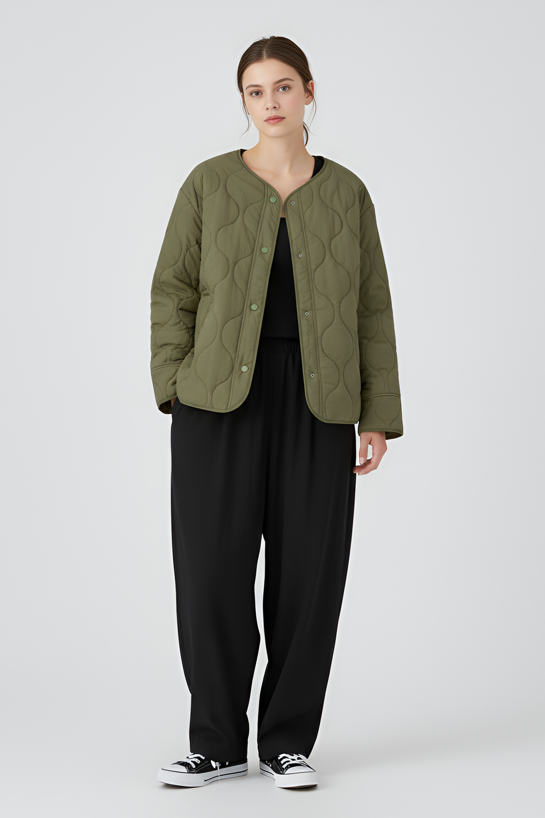 Person wearing a quilted green jacket, black leggings, and white sneakers on a gray background