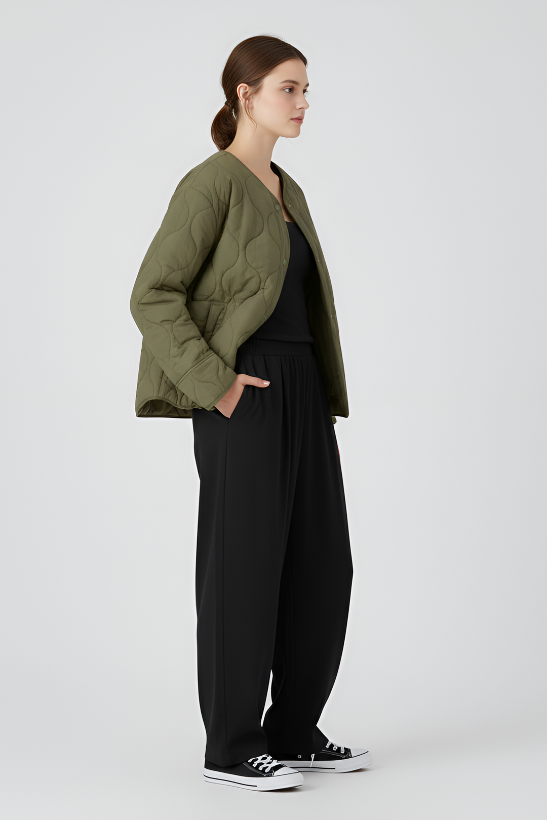 Person wearing a quilted beige jacket, black leggings, and white sneakers on a gray background