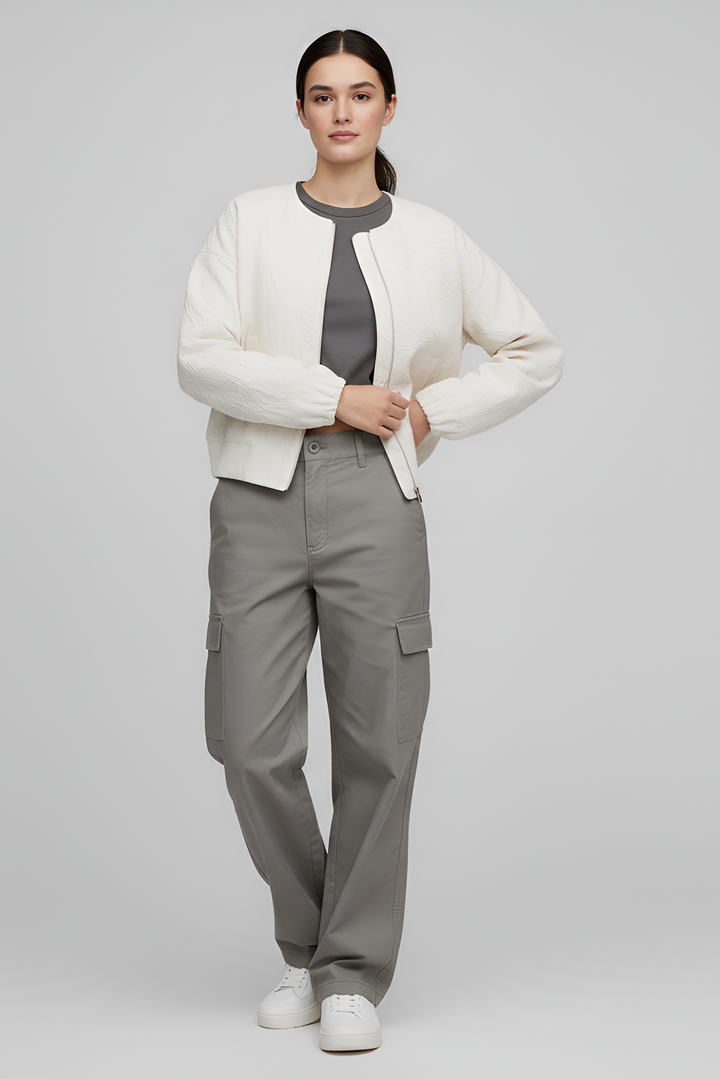 Person wearing a white cardigan, gray shirt, and gray cargo pants on a light gray background
