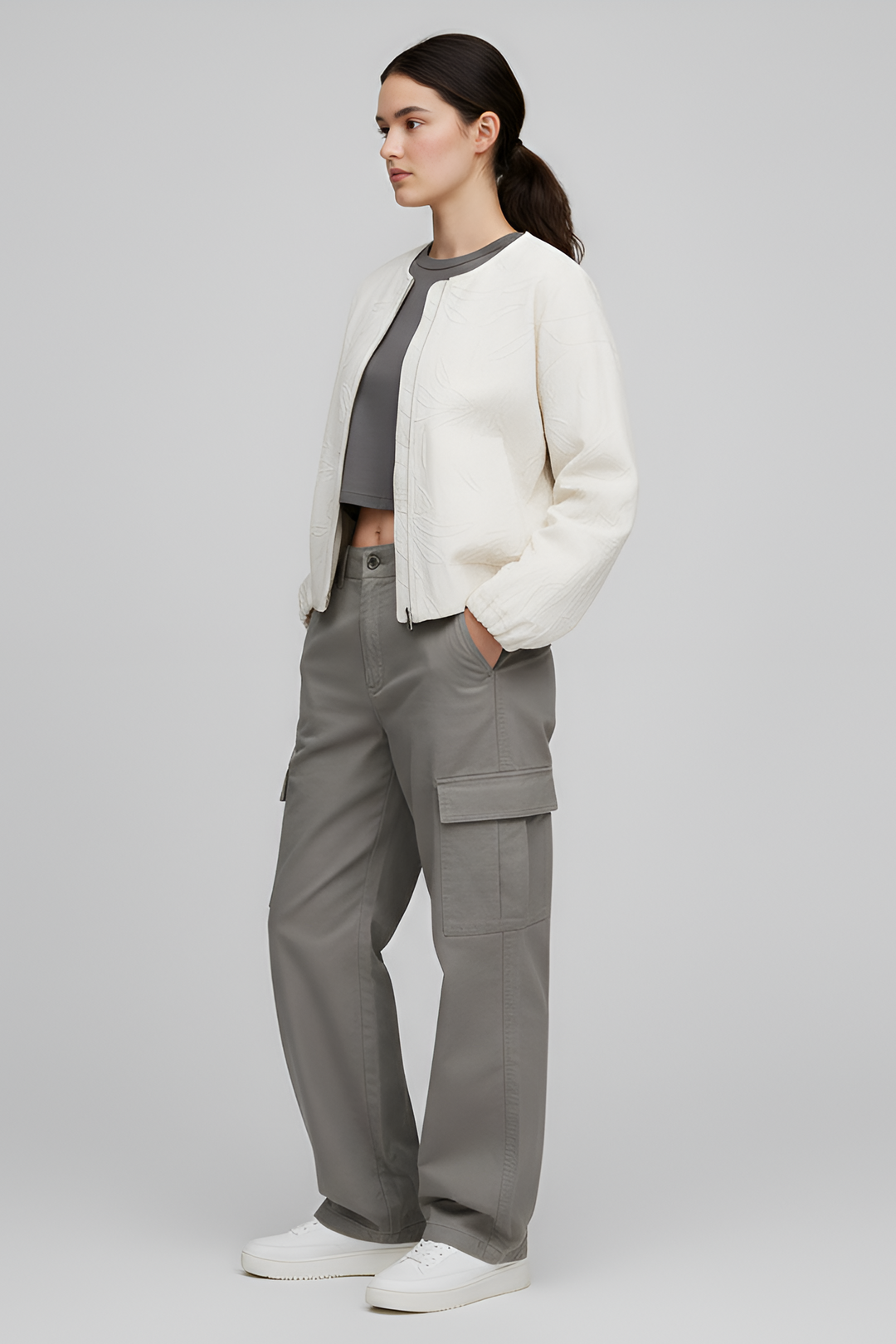 Person wearing a white jacket and gray cargo pants on a plain background