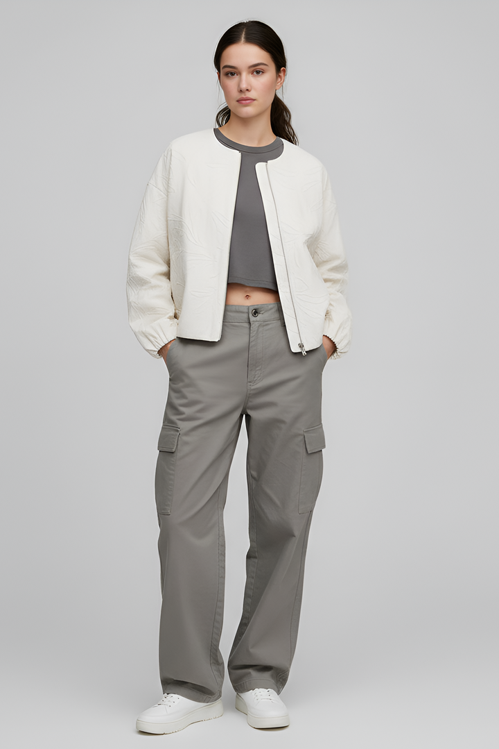 Person wearing a white jacket and gray cargo pants on a plain background