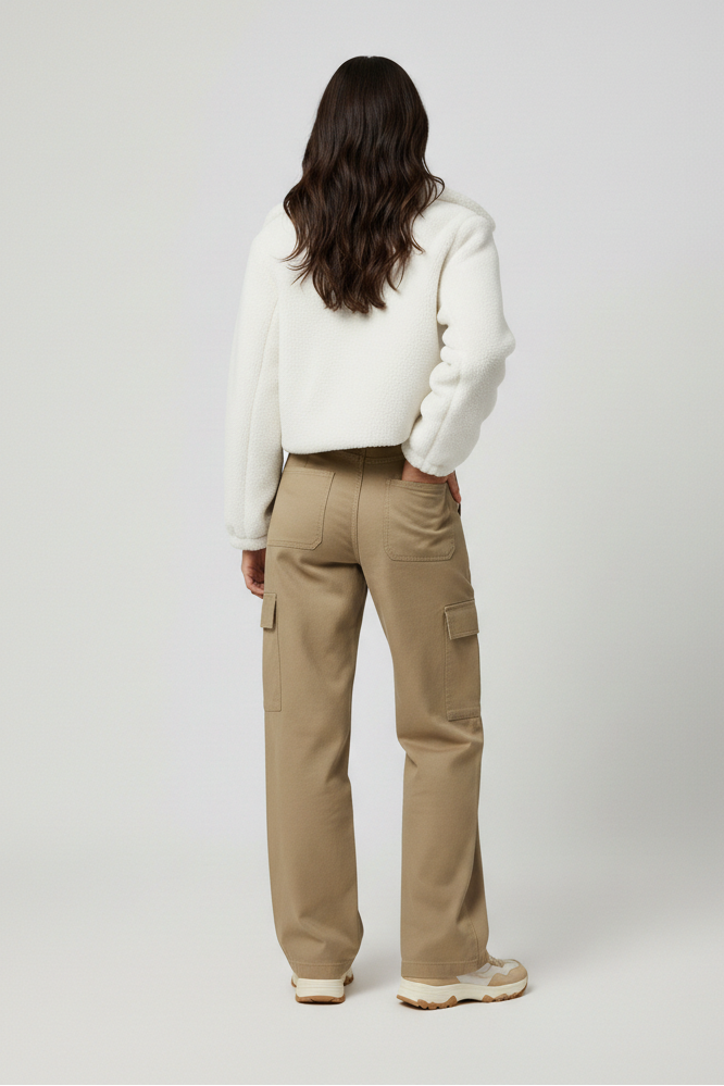 Person wearing a white sweater and beige pants on a light gray background