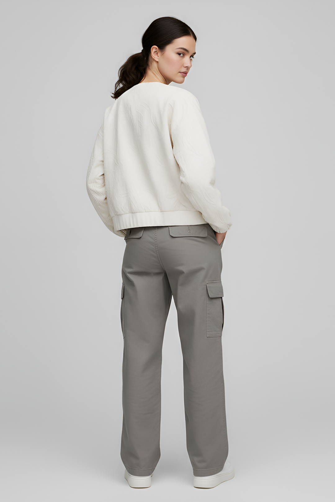 Person wearing a white sweater and gray cargo pants on a plain background