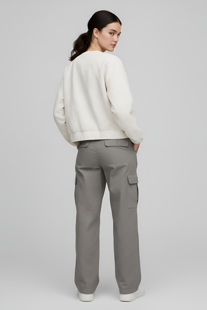 Person wearing a white sweater and gray cargo pants on a plain background