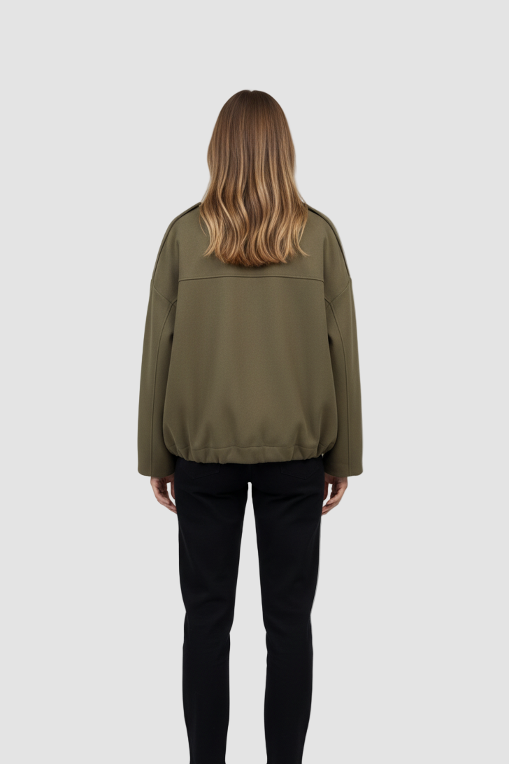 Person wearing an olive green jacket and black pants on a white background