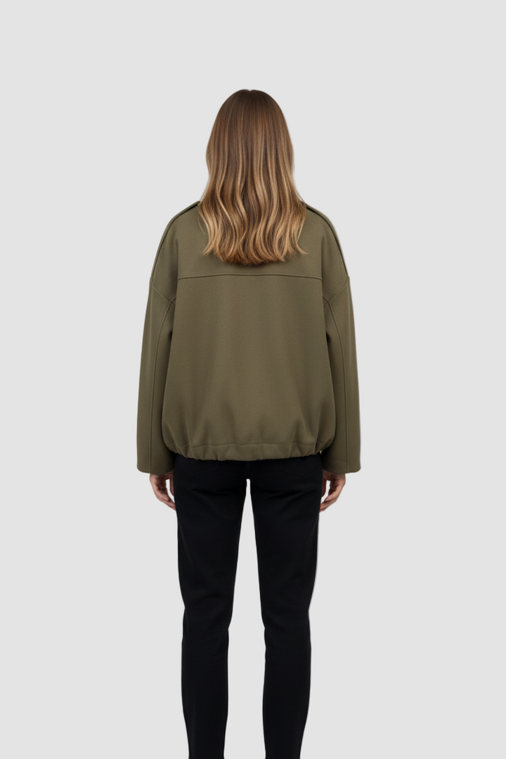 Person wearing an olive green jacket and black pants on a white background