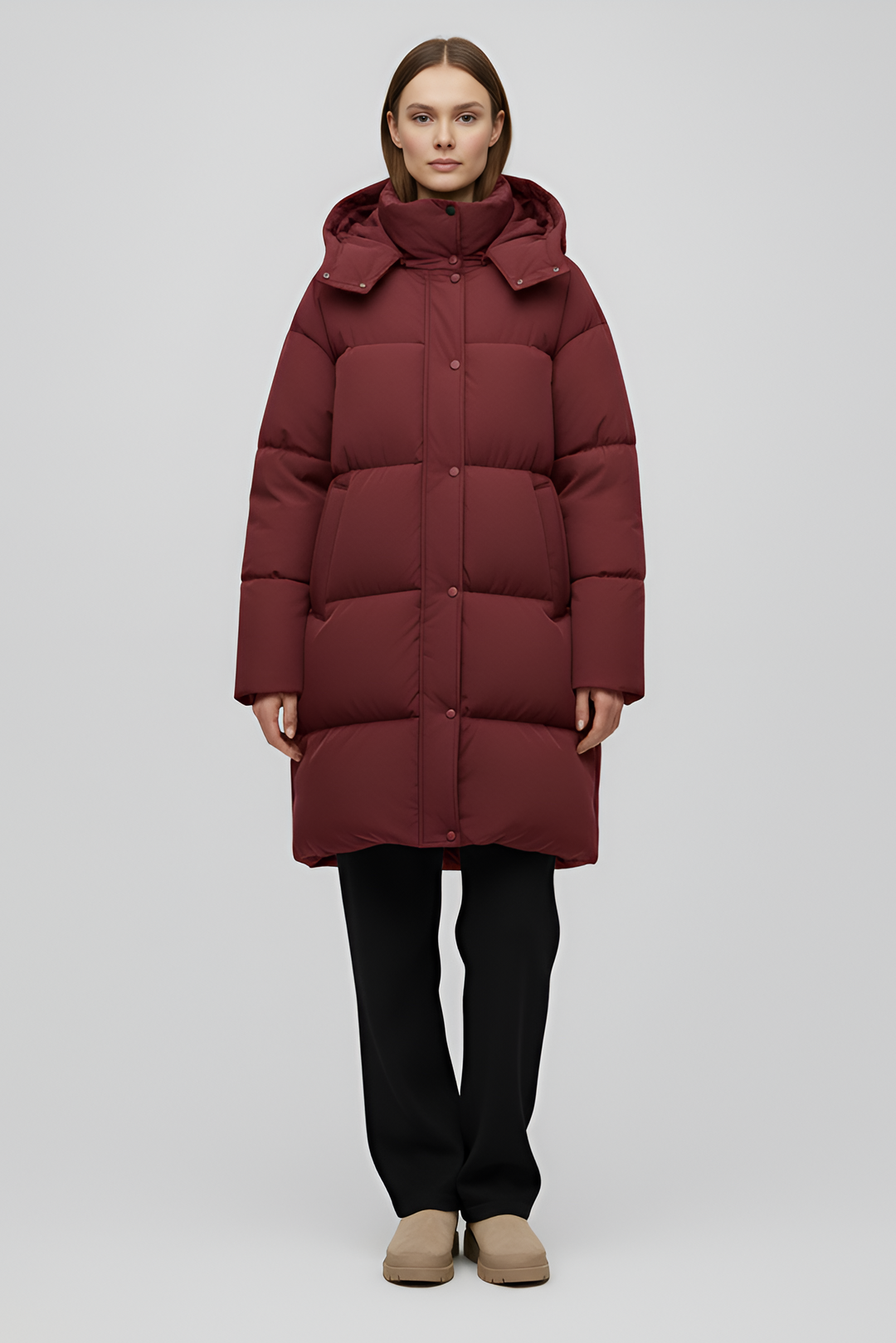 Person wearing a long burgundy puffer coat on a white background