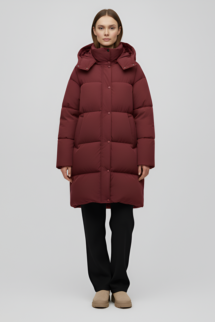 Person wearing a long burgundy puffer coat on a white background