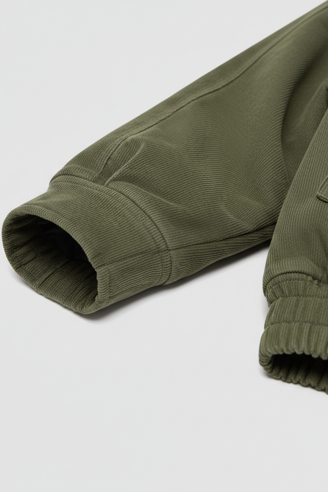 Rolled-up sleeve of a green jacket on a light gray background
