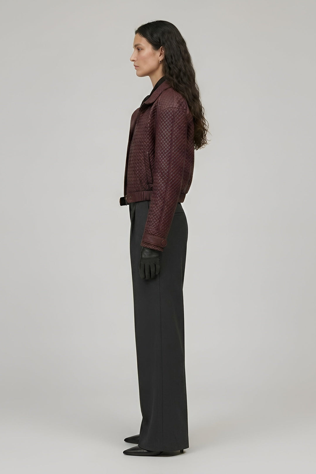 Woman wearing a patterned jacket and black pants on a plain background