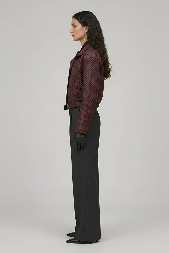 Woman wearing a patterned jacket and black pants on a plain background