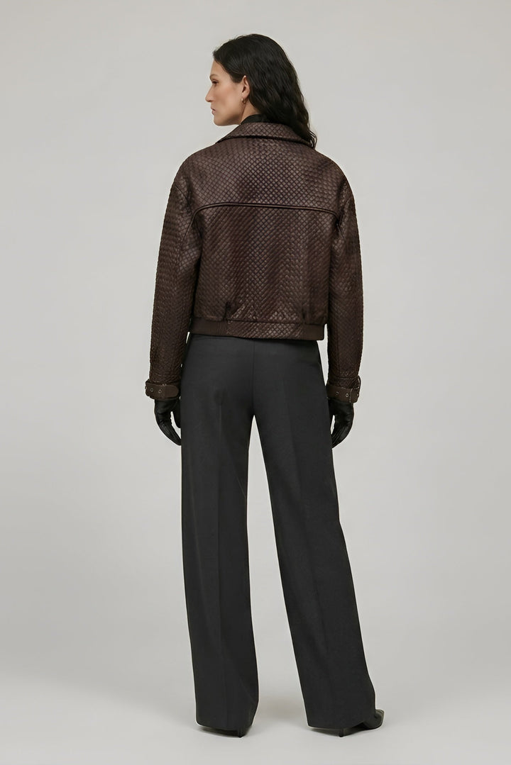 Person wearing a brown textured jacket and black pants on a plain background