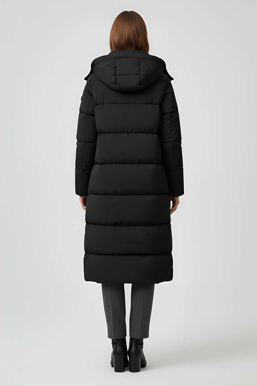 VALERIN Woman wearing a long black puffer coat on a light gray background