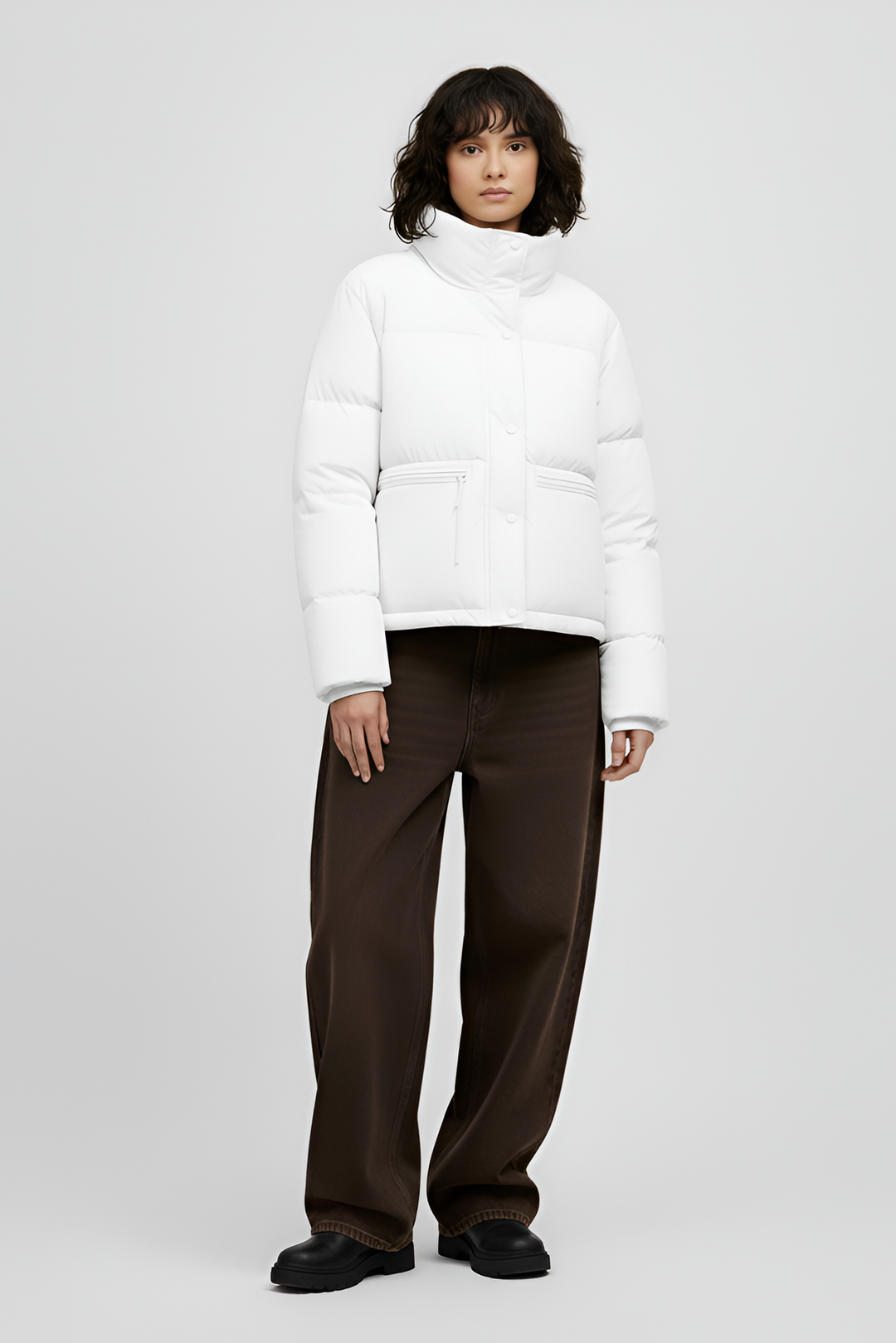 Woman wearing a white puffer jacket and pants on a light gray background