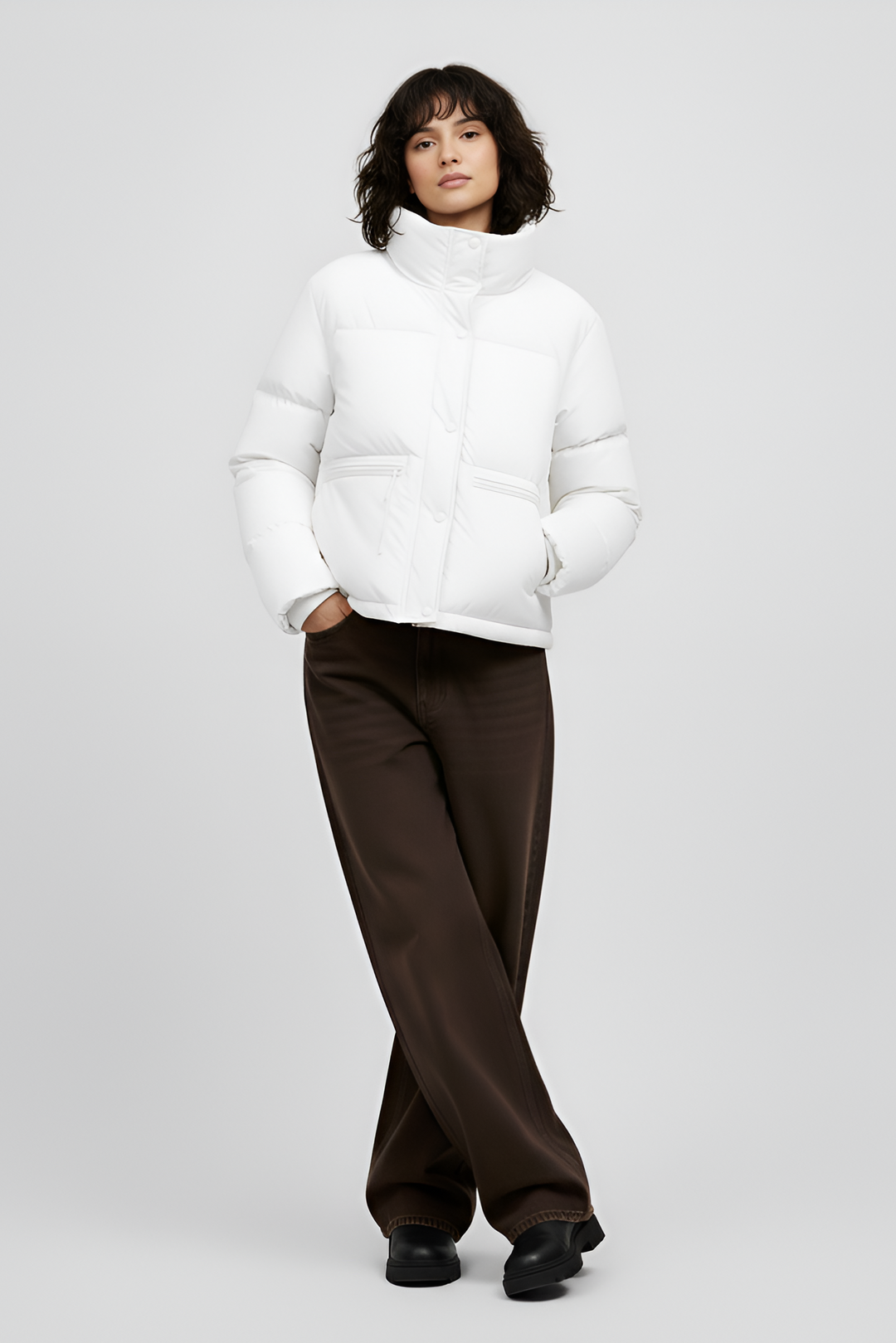 Woman wearing a white puffer jacket and pants on a light gray background