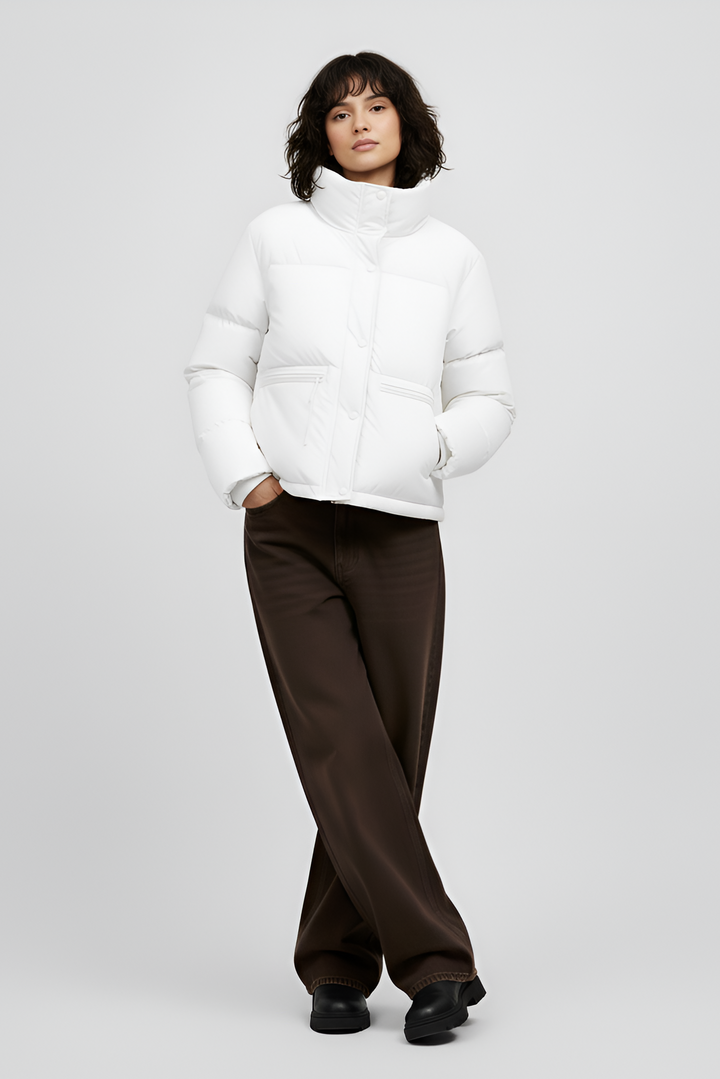 Woman wearing a white puffer jacket and pants on a light gray background