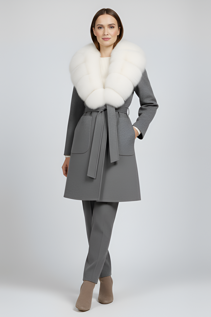 Woman wearing a gray coat with a white fur collar on a light gray background