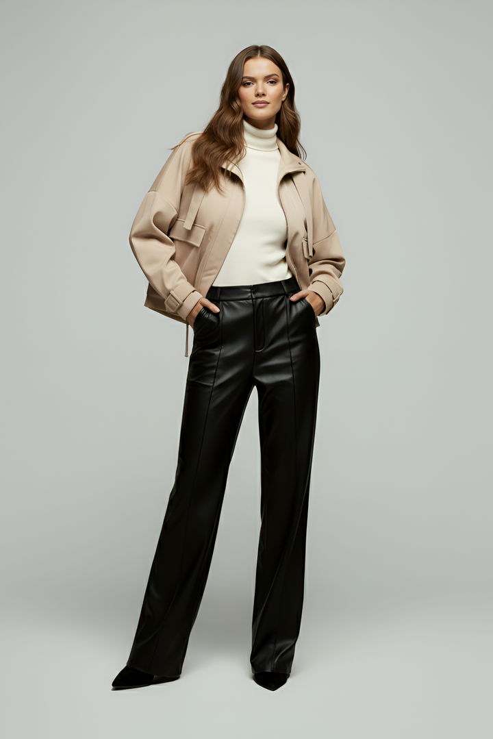 Woman wearing a beige jacket, white turtleneck, and black pants on a gray background