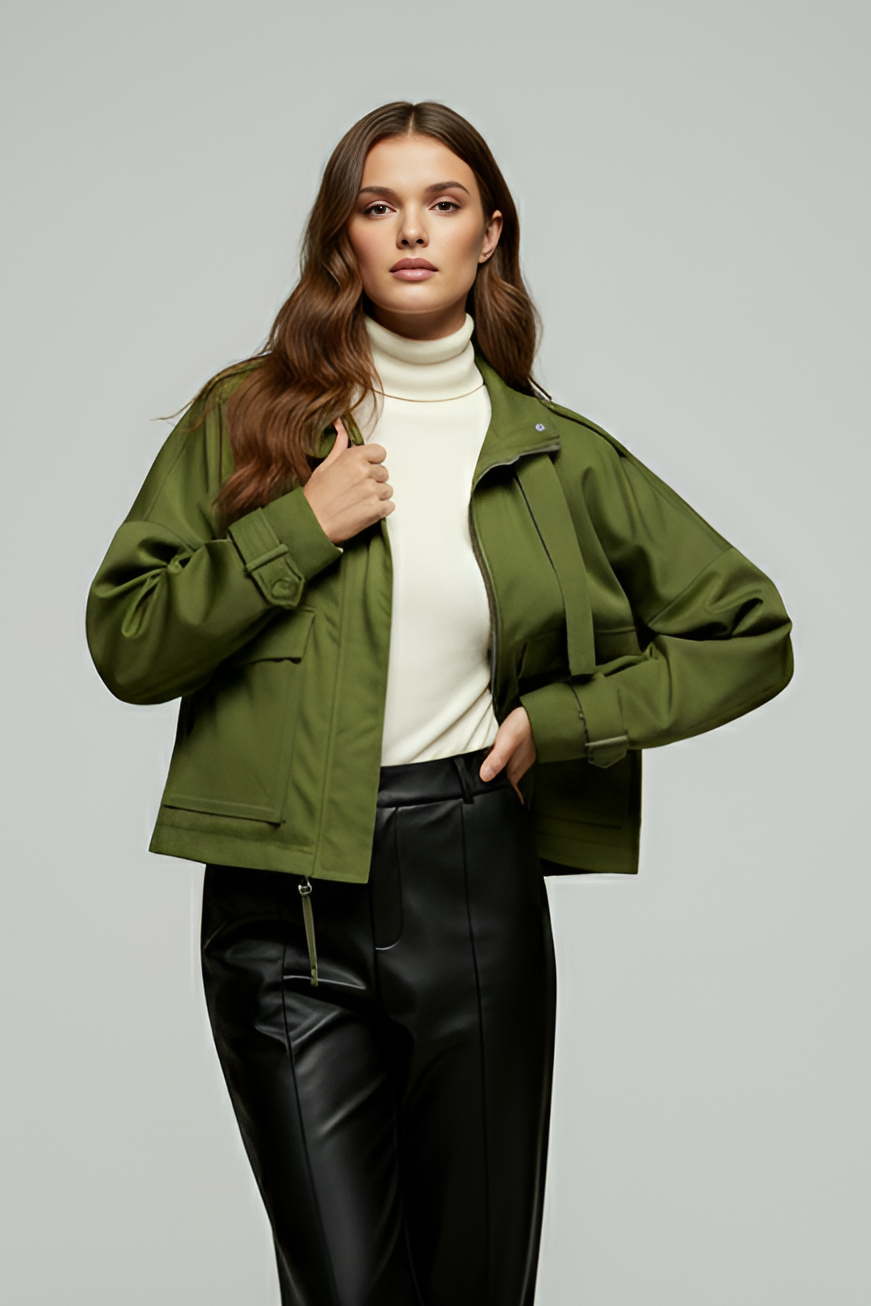 Woman wearing a green jacket and black pants on a gray background