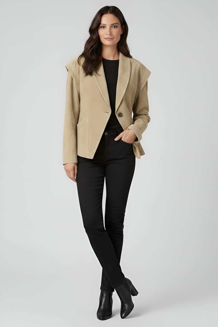 Woman wearing a beige blazer over a black top and pants on a white background