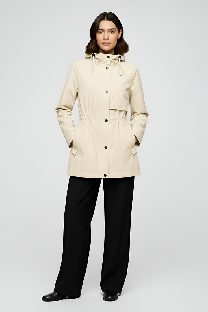 Woman wearing a beige coat and black pants on a white background