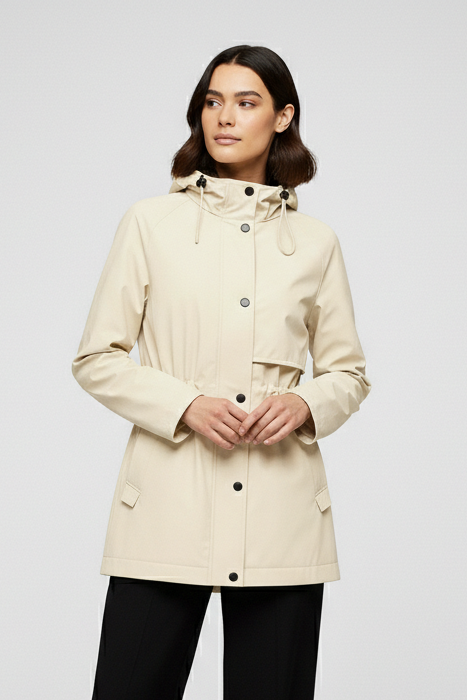 Woman wearing a beige coat and black pants on a white background