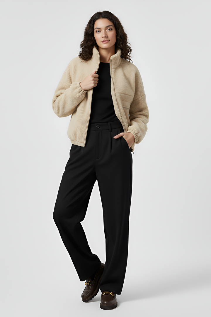Woman wearing a beige jacket and black pants on a white background