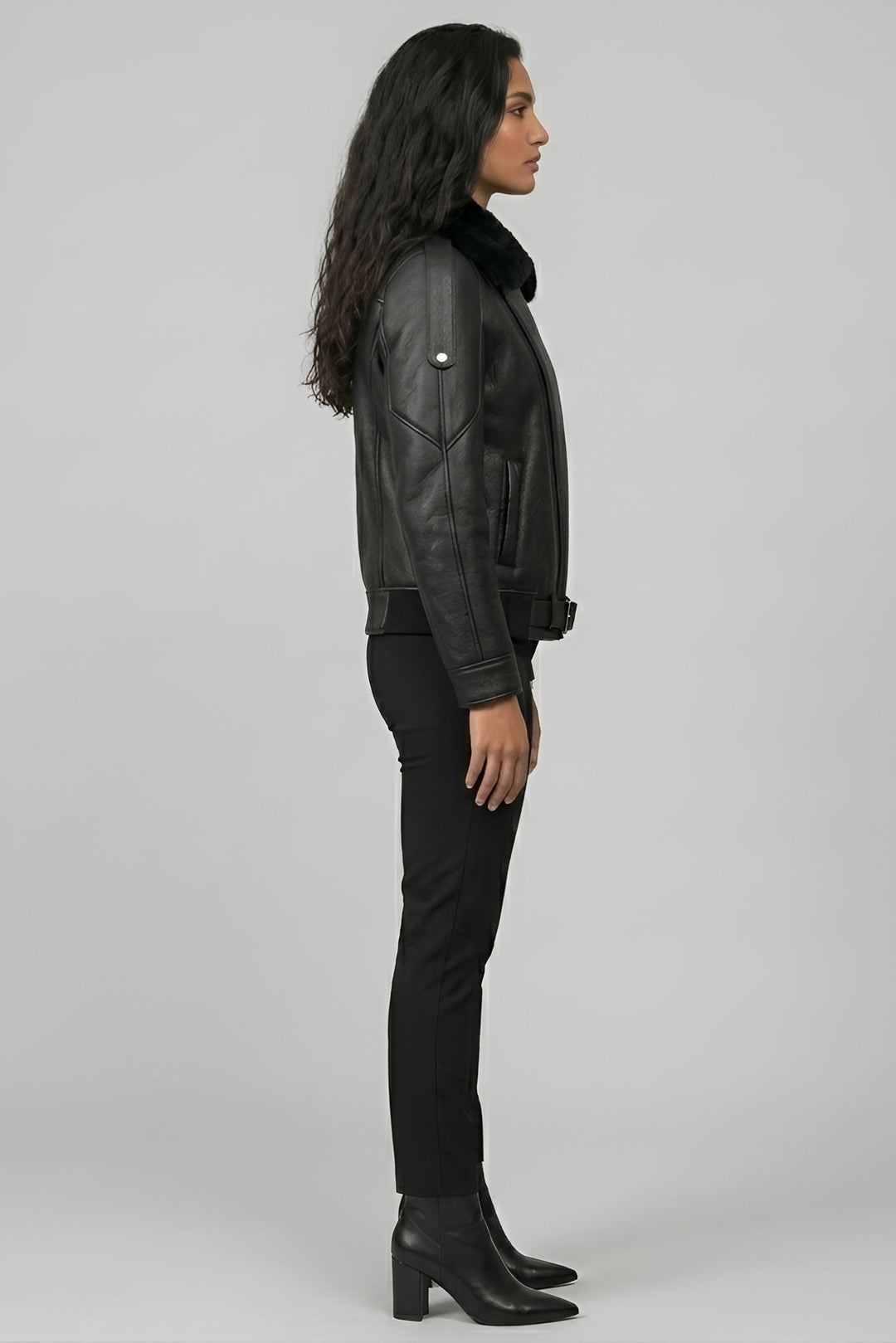 Woman wearing a black leather jacket and pants on a gray background