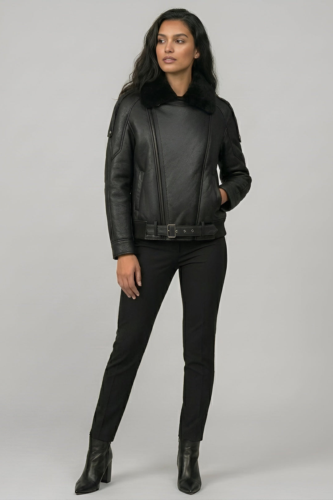 Woman wearing a black leather jacket and pants on a gray background