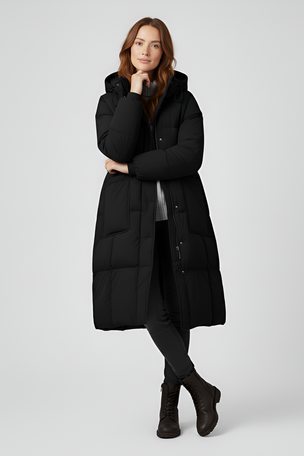 Woman wearing a black puffer coat on a light gray background