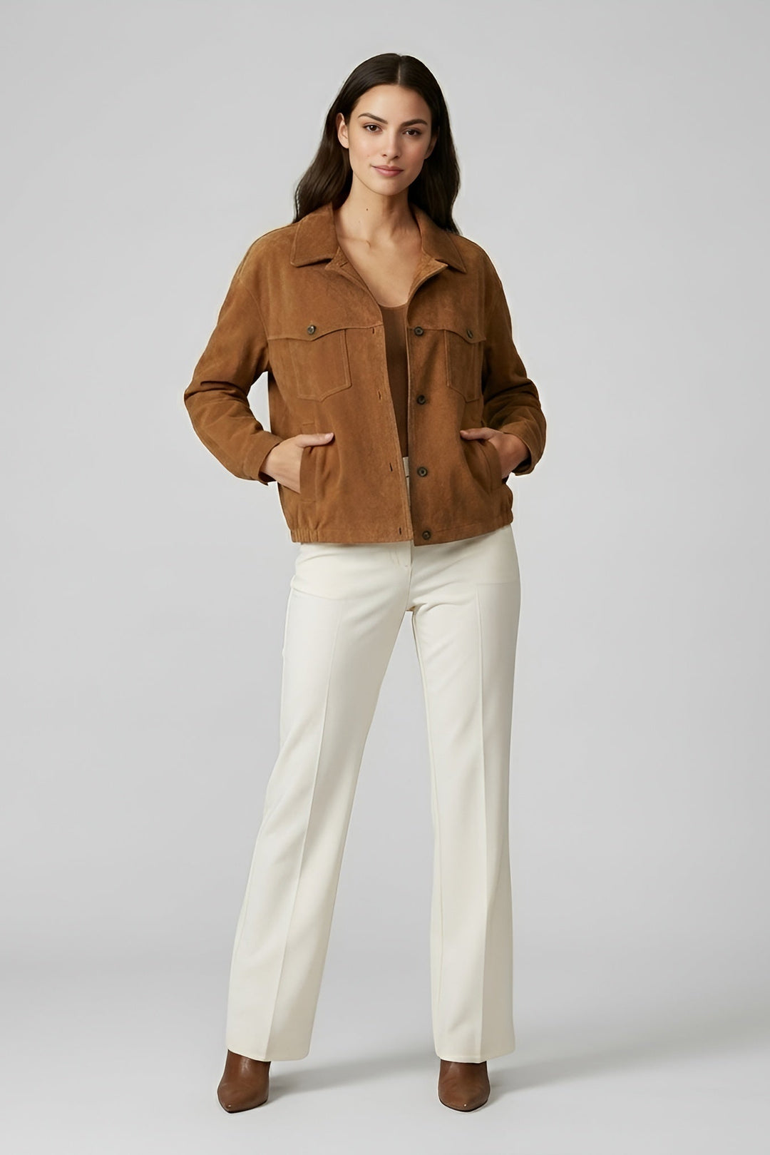 Woman wearing a brown jacket and white pants on a gray background