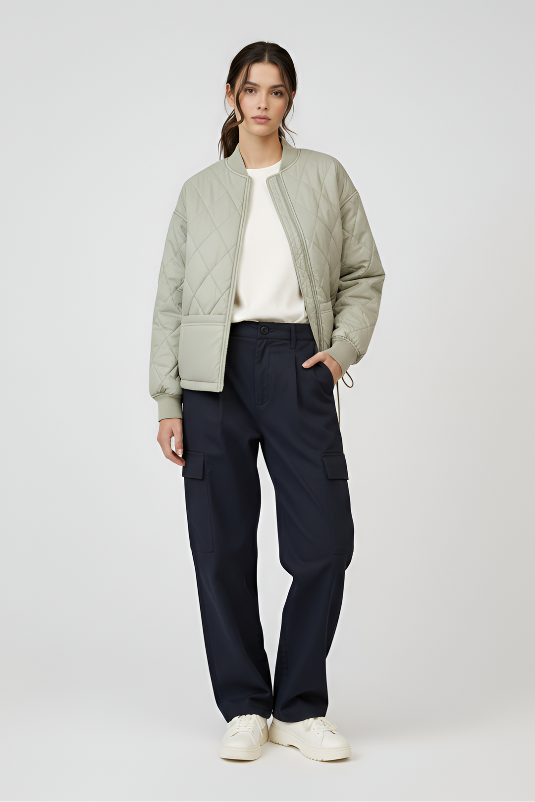 Woman wearing a light green puffer jacket and dark blue pants on a white background